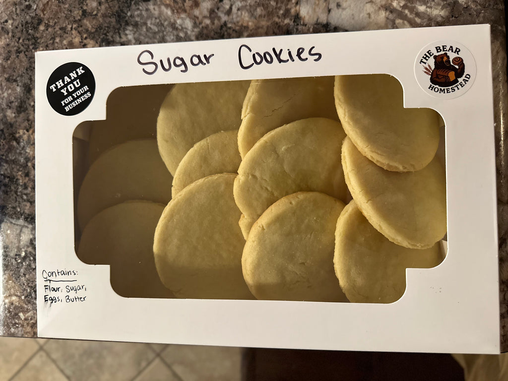 Box of sugar cookies with a clear window showing the cookies inside, on a countertop.